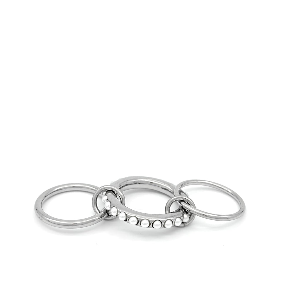 
                  
                    Anello in acciaio inox e Ottone, argentato composto da due fedi sottili,ed una spessa, tenute insieme da due anellini Argento, tono su tono.Nichel nei termini di legge. Si può indossare anche a più dita insieme. e perline sulla superfice. foto anello steso
                  
                